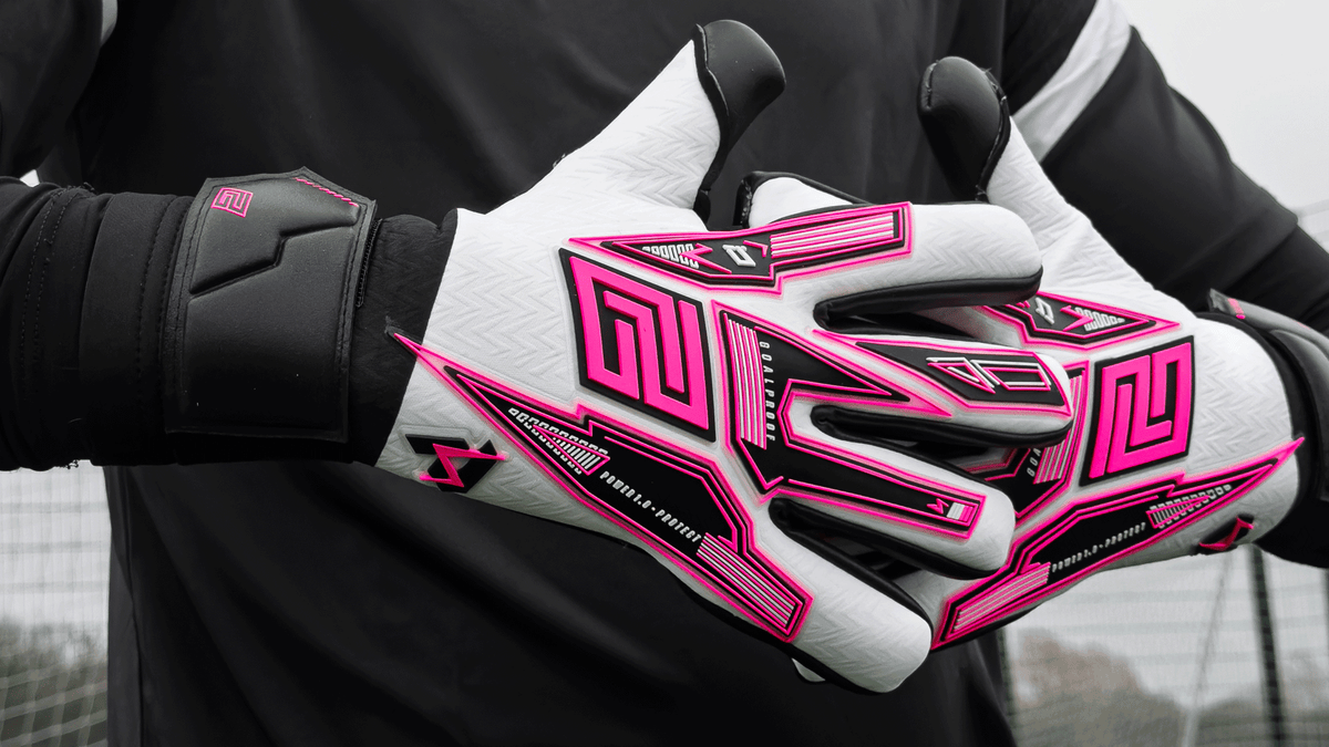 Close-up of a goalkeeper's hands wearing pink, black, and white Keeper iD Goalproof goalkeeper gloves